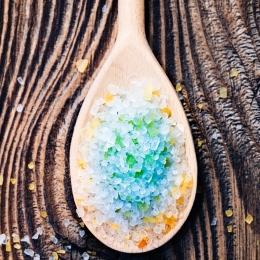 Colorful sea salt in wooden spoons put on old wooden table